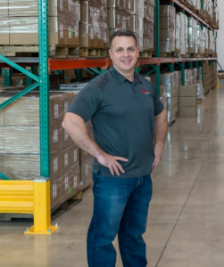 Jay Cohen, CEO of IQ Formulations standing in a warehouse with a shelving unit and product behind him.