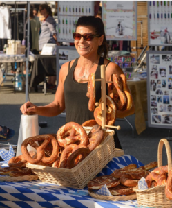 Campbell River. Street market with a person next to a soft pretzel table and more tables in the background.